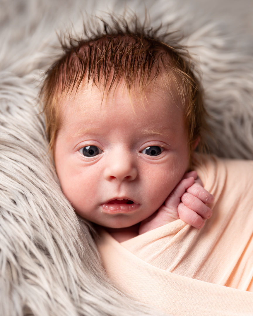 newborn baby girl awake with eyes open on grey blanket