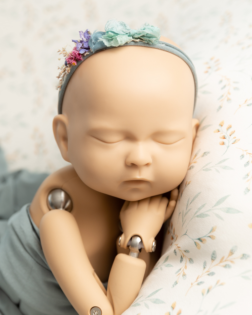newborn doll lying on a flowery blanket