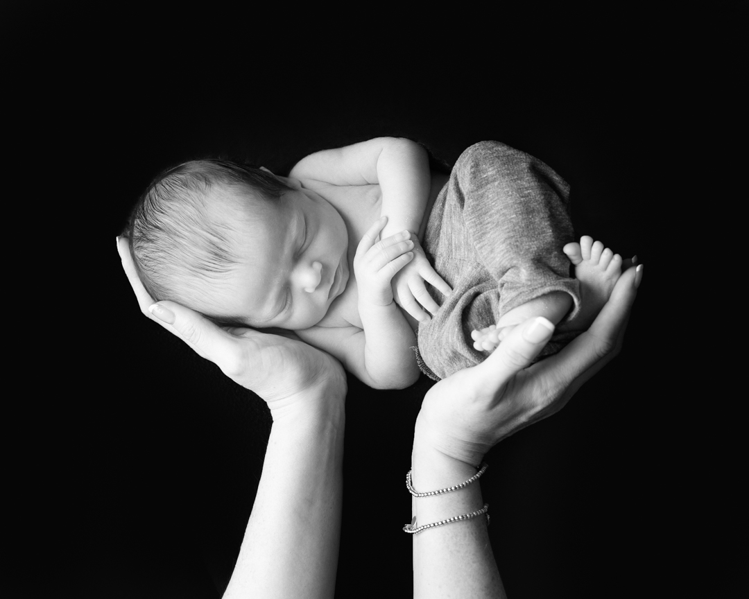 black and white image of baby being held up in mums hands