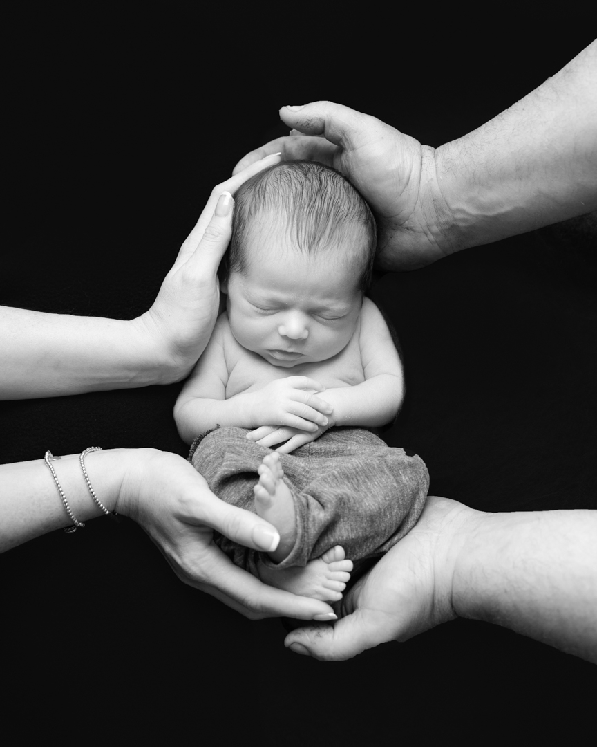 black and white photography of parents holding baby 