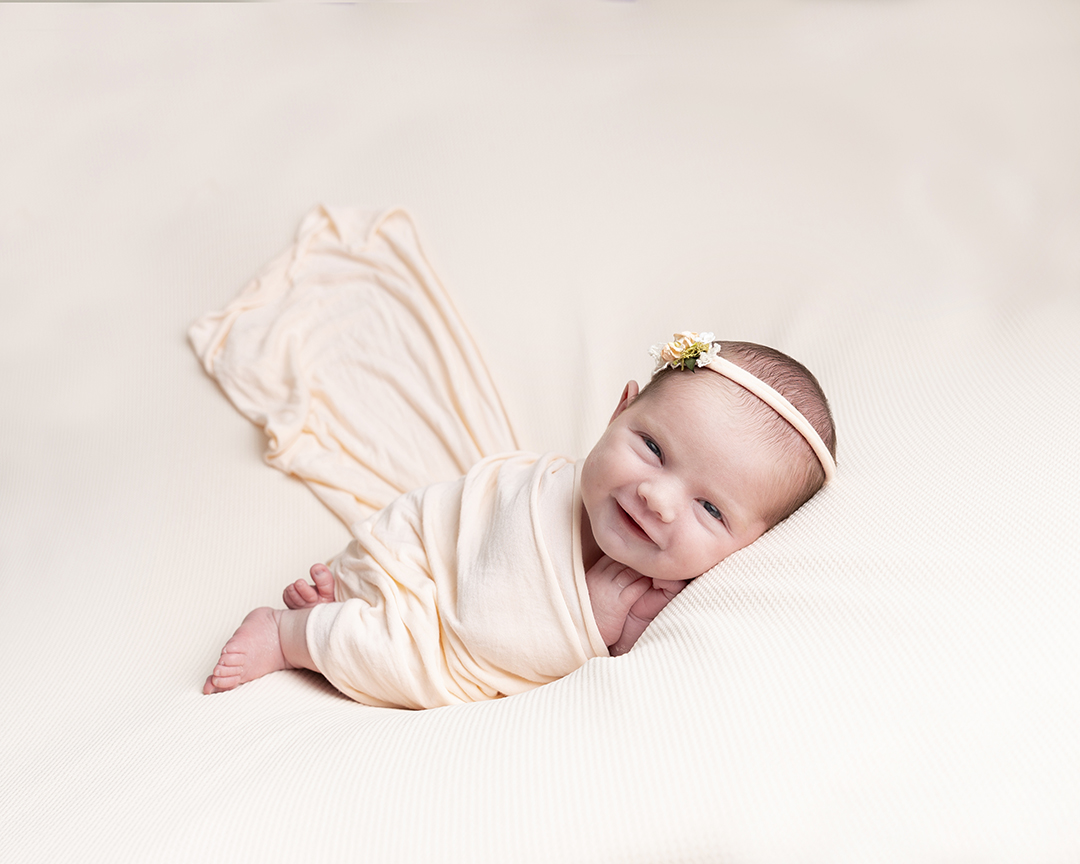 photography of a baby girl on a peach backdrop