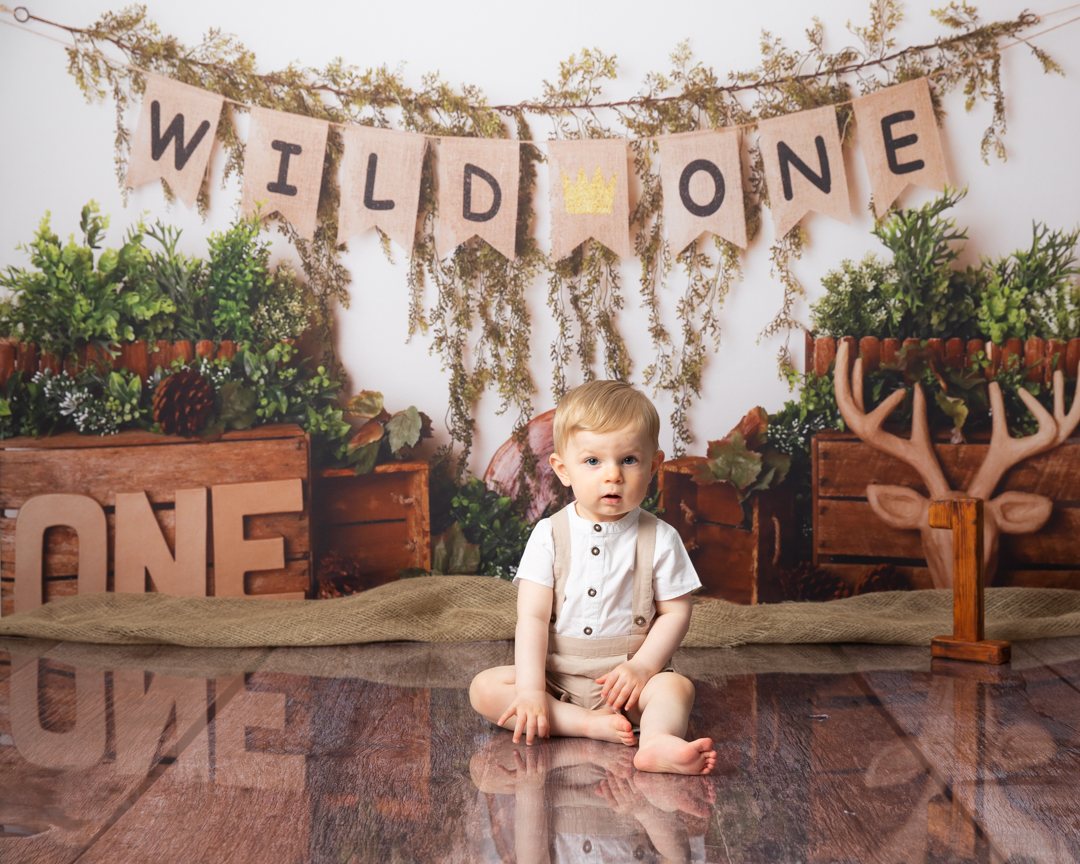 boy sitting on the floor with a decorated background celebrating his First birthday photoshoot Dumfries 