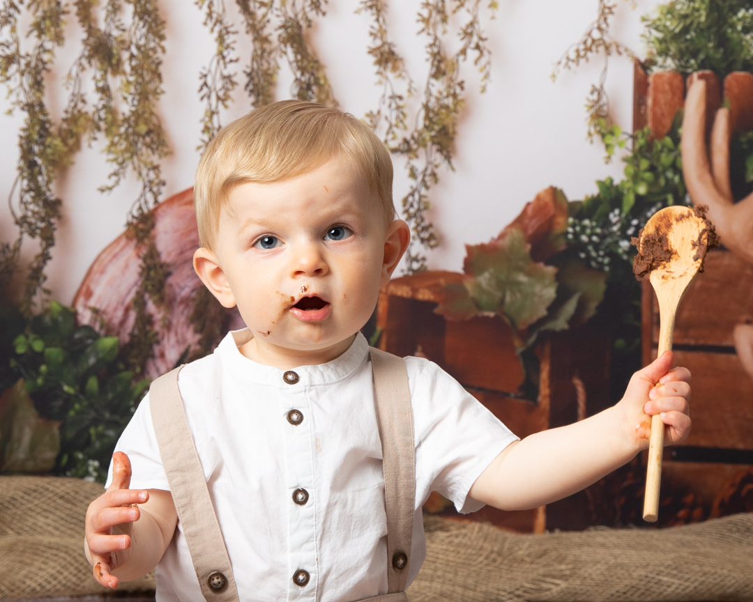 Boy eating cake holding wooden spoon