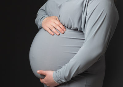 Pregnant lady wearing grey dress holding her bump