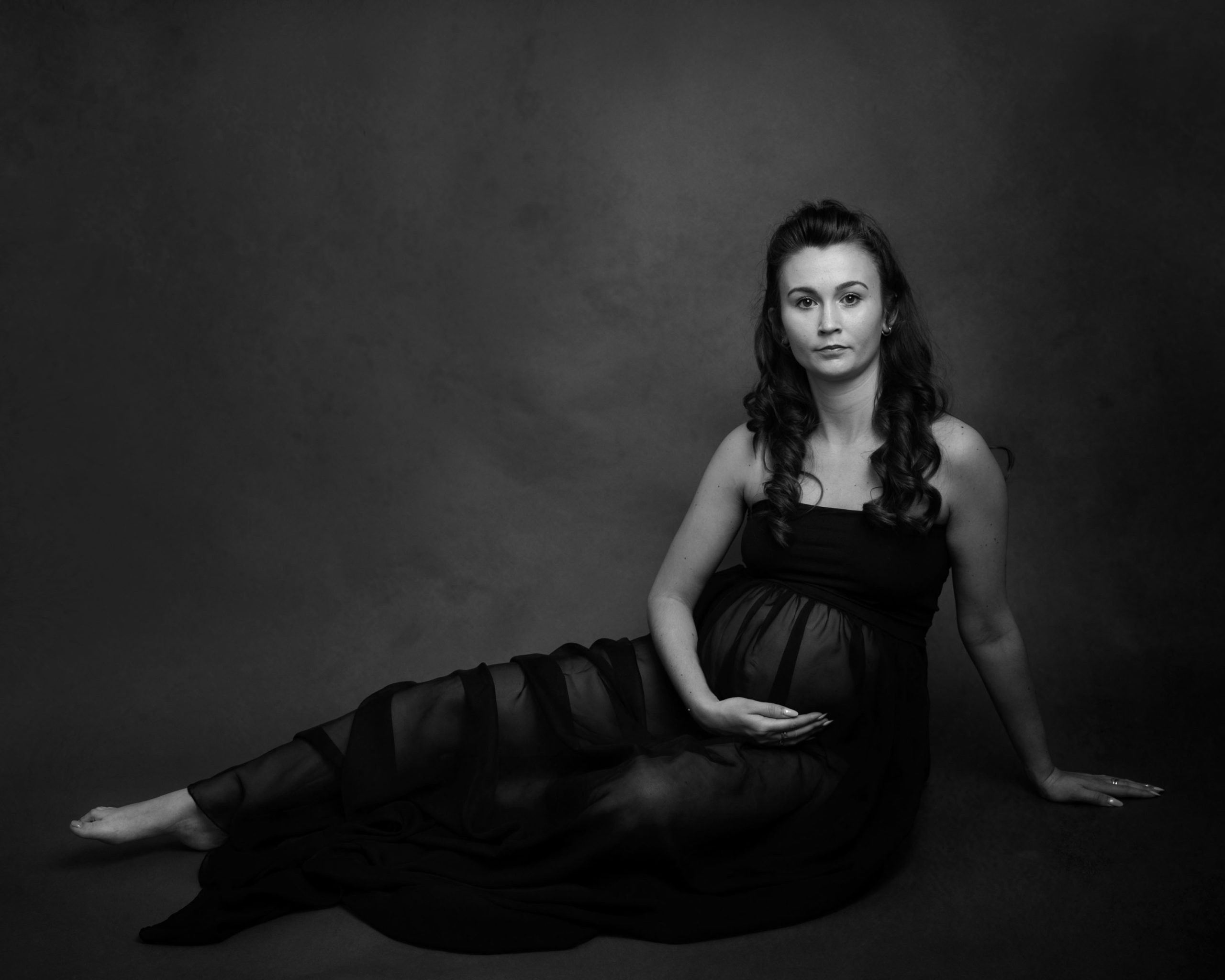 pregnant lady wearing a black dress sitting down by Newborn Photographer Dumfries 