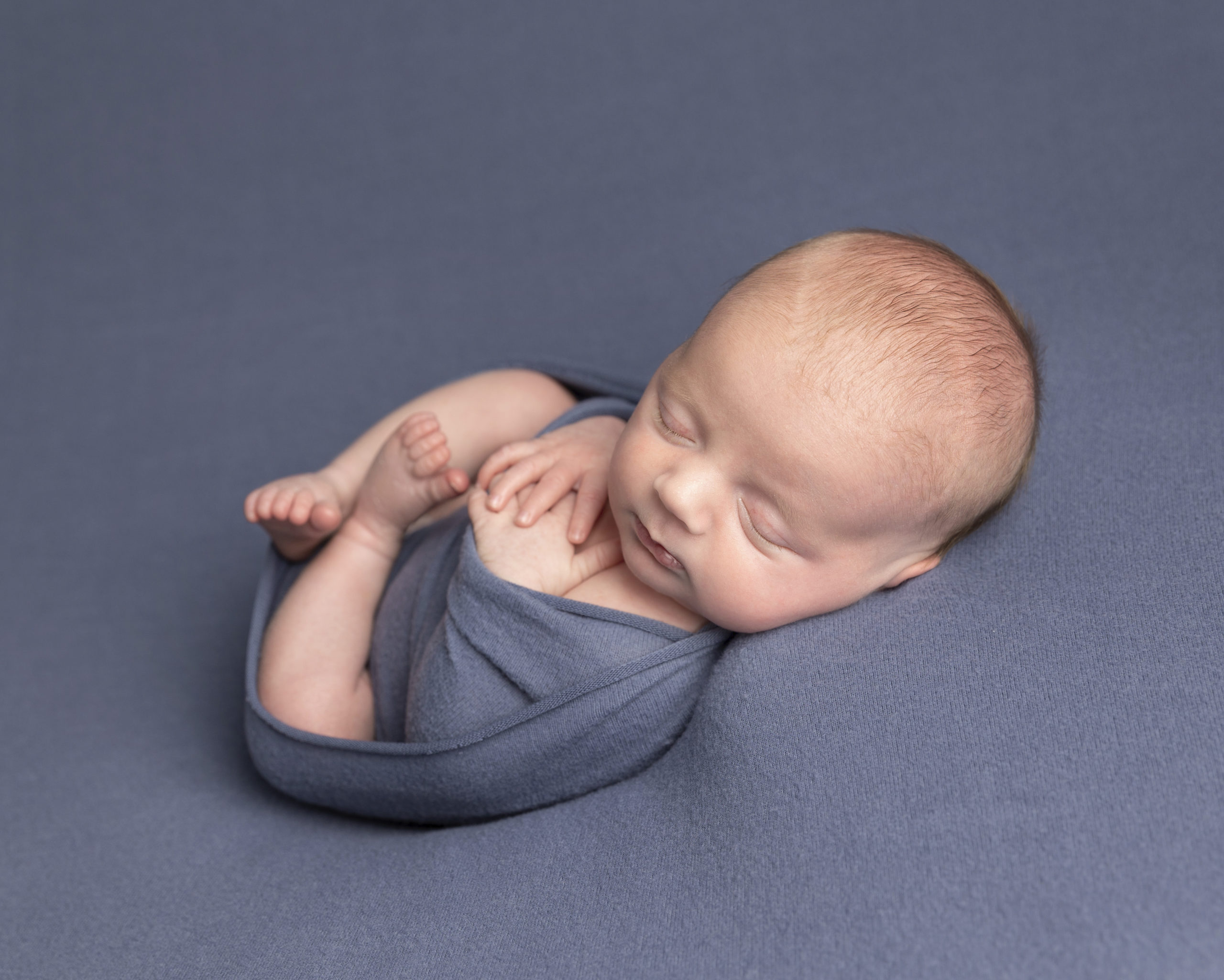 baby boy wrapped in a blue blanket during a photography session