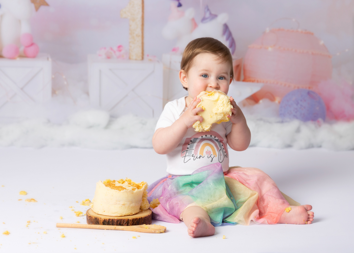 One year old girl eating cake during her first birthday celebration photoshoot