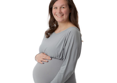 Lady smiling at camera wearing a maternity dress while pregnant