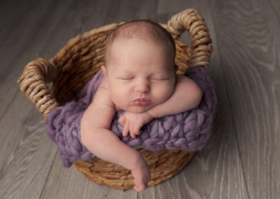 Baby girl lying asleep in a wicker basket