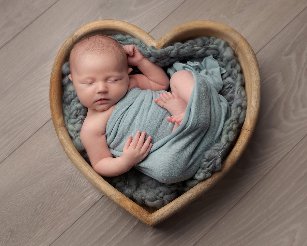 Baby girl all curled up sound asleep in a heart shaped bowl